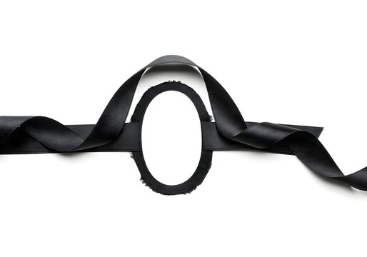 A ribbon made of traditional black crepe paper with a matte, textured finish, folded into a loop. On a white background, symbolizing traditional mourning