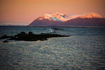 Snowy Mountain Range Above Dark Ocean at Sunset