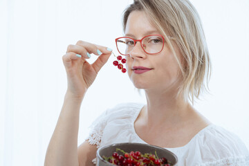Beautiful woman with red currants, healthy food with vitamins, and ingredients for cooking. 