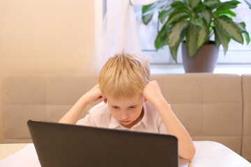 Young boy learning online at home using laptop