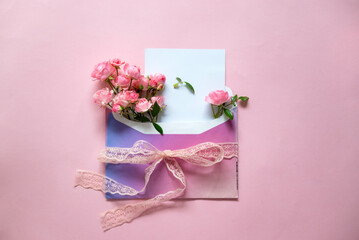 Envelope with pink roses and empty blank card on pink background