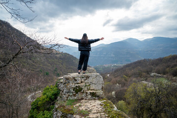 Obraz premium Young woman standing on a rock in the autumn cloudy mountain