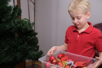 Child holding christmas ornaments decorating evergreen tree