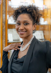 Young woman with afro hairstyle and dressed in black wears a pearl necklace in a jewelry store