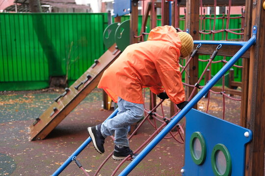 Child climbing rope net on autumn playground structure