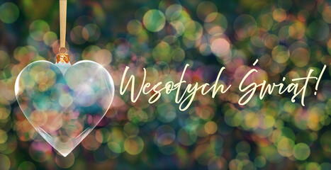 Poczt&oacute;wka bożonarodzeniowa - przezroczysta bombka choinkowa w kształcie serca na tle kolorowych rozmyć świateł bokeh z napisem Merry Christmas w języku polskim