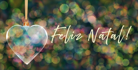 Poczt&oacute;wka bożonarodzeniowa - przezroczysta bombka choinkowa w kształcie serca na tle kolorowych rozmyć świateł bokeh z napisem Merry Christmas w języku portugalskim