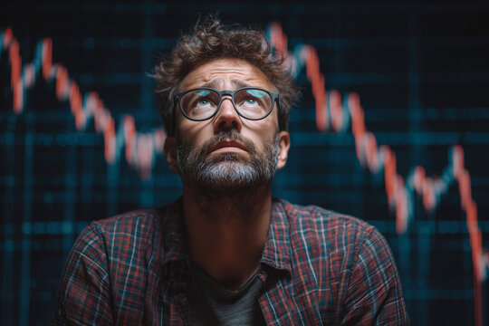 A man with glasses is looking at a graph with a downward trend