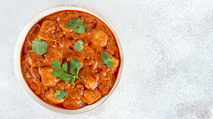 Indian butter chicken curry in a white bowl with fresh cilantro on white background. Top view. Copy space. Banner