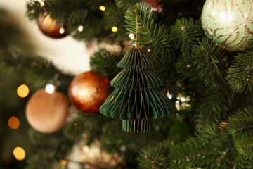 Festive green tree ornament hanging on a Christmas tree with warm lights and colorful decorations