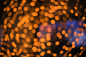 Bright orange bokeh lights create a warm, festive atmosphere during a night event in a city center