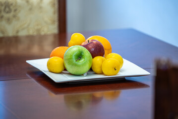Fruits in a vase on a glass table.