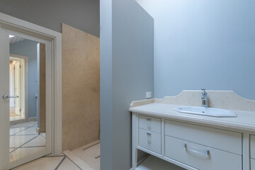 This contemporary bathroom features a clean design with a white vanity, a spacious shower area, and light blue walls