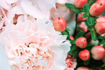 Close-up of soft pink peonies, hydrangeas, and red hypericum berries in a romantic floral arrangement