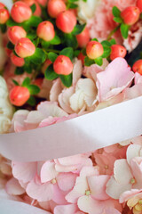 Elegant floral arrangement with pink hydrangeas, red hypericum berries, and white ribbon, perfect for wedding or romantic decor
