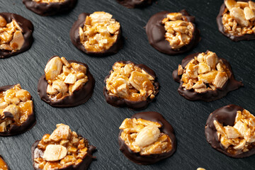 Chocolate Florentines cookies with almonds on a stone board.