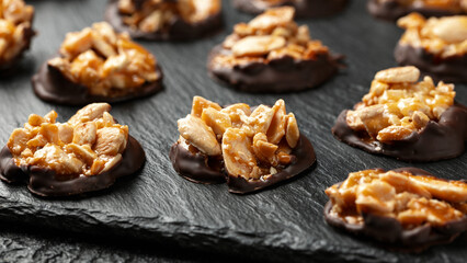 Chocolate Florentines cookies with almonds on a stone board.
