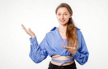 Cheerful young woman in casual outfit on white background, confidently pointing to empty space suitable for advertisement, message, slogan or graphical insertion, studio photo