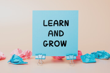 Learn and Grow: text on a sticky note. Concept of Positive and Motivational Message of Continuous Learning and Progress. Blue Note on a Neutral Background