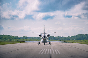 Seen from behind a small corporate jet taxing to the end of the runway at a small regional airport, Ontario Canada. Selective focus to soften the background. © Paul