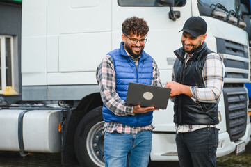 Truck drivers discussing logistics and fleet management with laptop