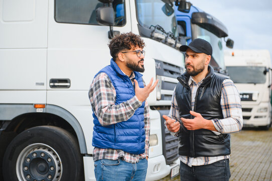 Truck drivers discussing logistics in front of semi trucks