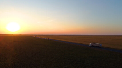 a truck driving on the highway at sunset, drone view