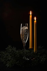 champagne and candles stand in the pine needles.
