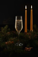 champagne and candles stand in the pine needles.