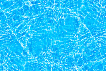 Blue water with ripples on the surface. Defocus blurred transparent blue colored clear calm water surface texture with splashes and bubbles. Water waves with shining pattern texture background.
