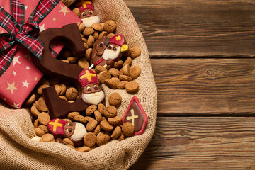 Festive Treats and Gifts. Sinterklaas chocolates and cookies in a burlap sack on a wooden table.