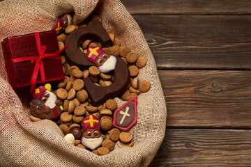 Festive Treats and Gifts. Sinterklaas chocolates and cookies in a burlap sack on a wooden table.