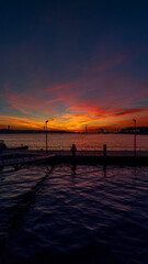 Naklejka premium Sunset seen from Cais das Colunas in Lisbon with a view of the 25 de Abril Bridge