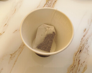Tea bag resting in an empty cup on a countertop