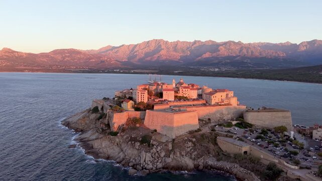 Aerial view of calvi citadel at sunrise with serene waters. Fortress with marina. Corsica. France