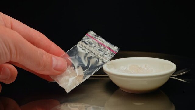 Drug dealer preparing and packaging Fentanyl Crystal meth or Crack Cocaine for sale and distribution. Drug trafficking and addiction crises. Crystals use in glass tube or stems and primarily smoking.