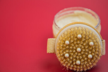 Body scrub in a glass jar features a textured brush lid, placed on a vibrant red background, emphasizing beauty and self-care for skincare enthusiasts