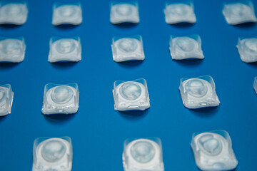Contact lenses in disposable containers lie on a blue background at the same distance. The concept of ophthalmology, medicine, vision correction, eye care. High quality photo