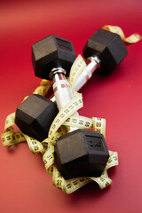 Dumbbells placed on a measuring tape, highlighting fitness and health themes, with a striking red background creating an energetic atmosphere