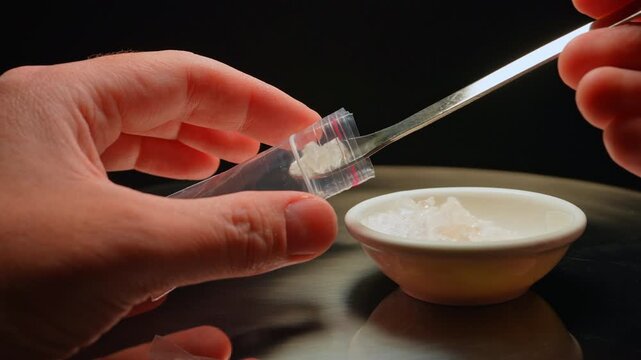 Drug dealer preparing and packaging Fentanyl Crystal meth or Crack Cocaine for sale and distribution. Drug trafficking and addiction crises. Crystals use in glass tube or stems and primarily smoking.