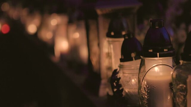 Row of memorial candles viewed from the side, only candlelight illuminating the scene, with most of the background blurred