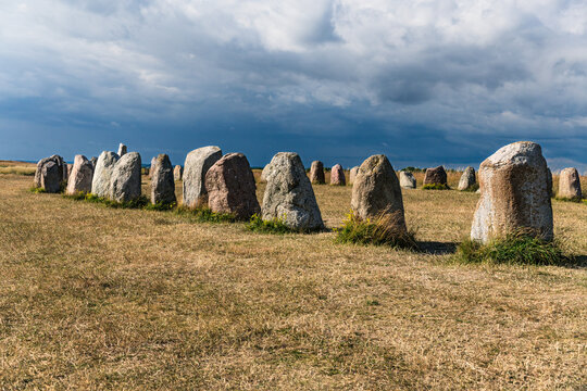 Ale stones monument standing in the golden field under a cloudy sky, representing a ship setting and offering a glimpse into ancient Nordic history and heritage