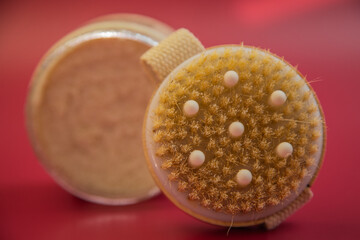 Exfoliating brush with soft bristles and a convenient strap, positioned on a bright red background, highlighting essential beauty tools for skincare routines