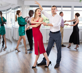 Fototapeta premium Energy man and woman are dancing classic version of waltz in couple during lesson at studio. Leisure activities and physical activity for positive people.