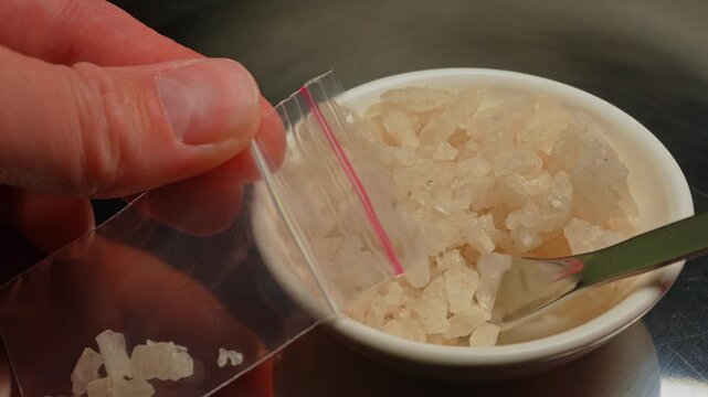 Drug dealer preparing and packaging Fentanyl Crystal meth or Crack Cocaine for sale and distribution. Drug trafficking and addiction crises. Crystals use in glass tube or stems and primarily smoking.