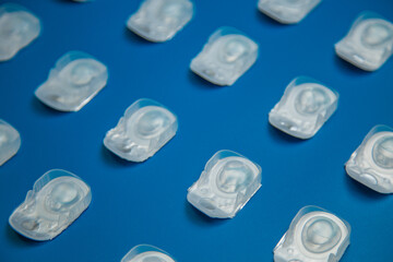 Folding is a one-day contact lens in a disposable protective case, which lie on a blue background. The concept of ophthalmology, vision correction, eye care. High quality photo