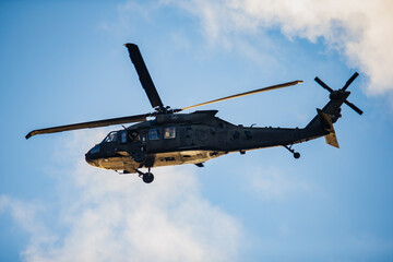 Armed forces helicopter showing tactical fuselage, dual rotor system and underbelly equipment in clear airborne movement against illuminated sky
