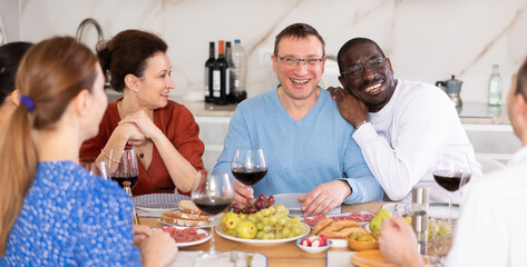 Happy companions congregated around a festive table, participating in animated discussions and enjoying the delights of red wine