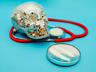 Two lines of white powder of illegal drugs substance on round small mirror on blue medical...