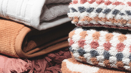 A stack of towels with a pink and white towel on top. The towels are folded and stacked on top of each other